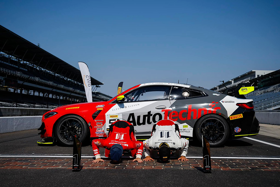 Race car drivers Colin Garrett & Zac Anderson kiss the bricks at Indy in front of their race car